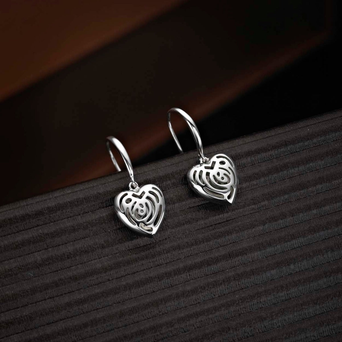 Dangling Heart 925 Sterling Silver Drop Earrings on black surface